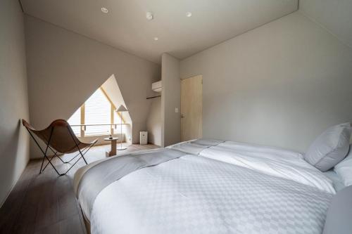 a bedroom with a large white bed and a window at ERUSA Rusutsu in Rusutsu