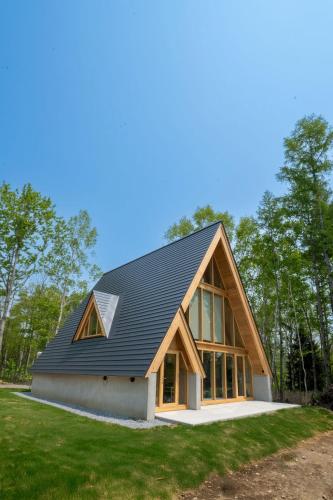a house with a black roof on top of a yard at ERUSA Rusutsu in Rusutsu