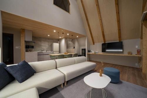 a living room with a white couch and a kitchen at ERUSA Rusutsu in Rusutsu