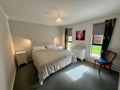 a bedroom with a bed and a chair and a window at 15b Caverhill Close in Hanmer Springs