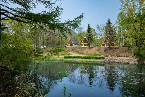 a view of a pond in a park with trees at ERUSA Rusutsu in Rusutsu