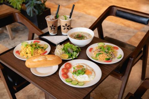a wooden table with plates of food on it at HAKU Boutique Hotel Tuy Hoà - APEC Mandala in Tuy Hoa