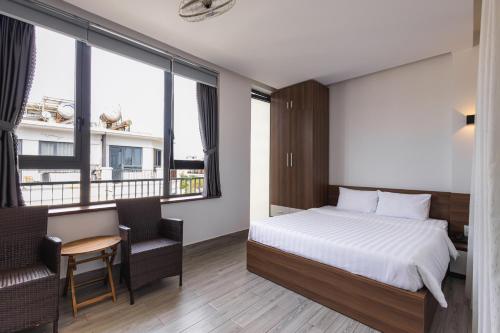 a hotel room with a bed and a table and chairs at HAKU Boutique Hotel Tuy Hoà - APEC Mandala in Tuy Hoa