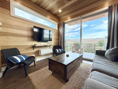 a living room with a couch and a tv and a large window at Escalante Escapes Fox Tail- Loft Escape in Escalante