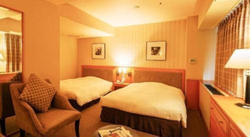 a hotel room with two beds and a chair at Diamond Hotel Tokyo in Tokyo