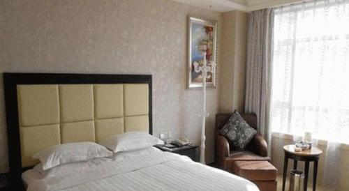 a bedroom with a bed and a chair and a window at Fuzhou Xin Zi Yang Hotel in Fuzhou