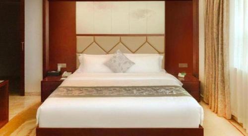 a bedroom with a large bed with white sheets at Fuzhou Xin Zi Yang Hotel in Fuzhou