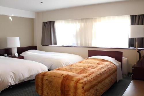 a hotel room with two beds and a large window at Oita Century Hotel in Oita