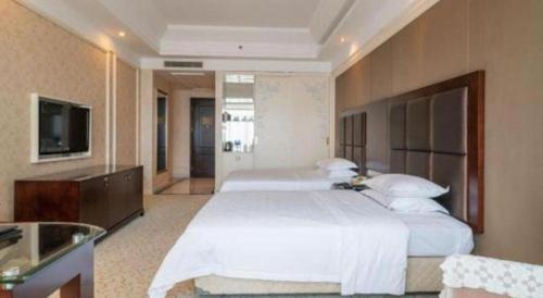 a bedroom with two beds and a flat screen tv at Jinjiang Grandlink Hotel in Quanzhou