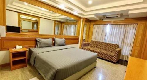 a bedroom with a bed and a couch and a television at New Siya in Maha Sarakham