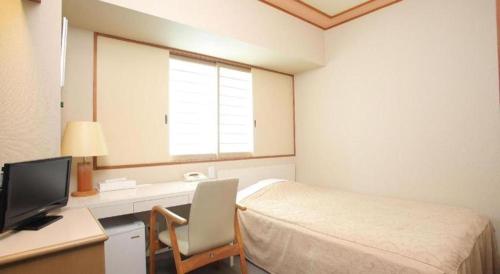 a bedroom with a bed and a desk with a television at Hotel Grand Shinonome in Tsukuba