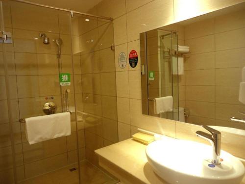 a bathroom with a sink and a shower with a mirror at GreenTree Inn Shangrao Qianshan hekou old town Xinjiang longting shell hotel in Shangrao