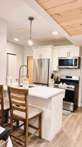 a kitchen with white cabinets and a kitchen island with chairs at Downtown 5B2B Apt, Sleeps 10, Near PPAC & Events in Providence