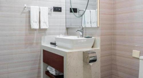 a bathroom with a sink and a shower with towels at Xana Lite Anqing Yuexi Swan Squre Branch in Yuexi
