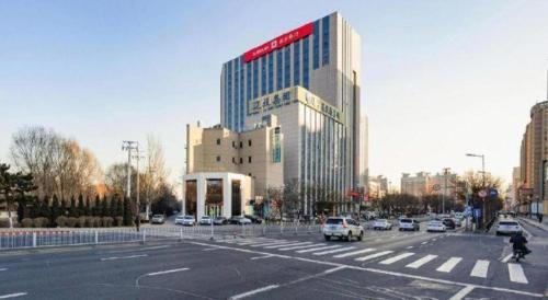 a large building in a city with a street with cars at Xana Lite Shenyang Beiling Park Liaoning Building Branch in Shenyang