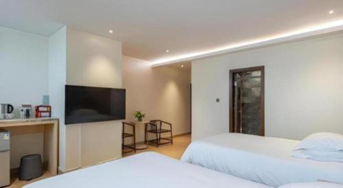 a bedroom with two beds and a flat screen tv at Leisurely Hotel Shenzhen in Shenzhen