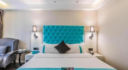 a bedroom with a large bed with a blue headboard at Xana Lite Shenyang Beiling Park Liaoning Building Branch in Shenyang
