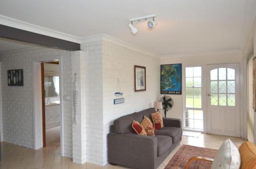 a living room with a couch and a brick wall at Sandpiper at Jervis Bay - Rustic Retreat in Callala Beach