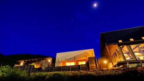 a house at night with the moon in the sky at Yufuin Luxury Villa -zakuro- in Yufuin
