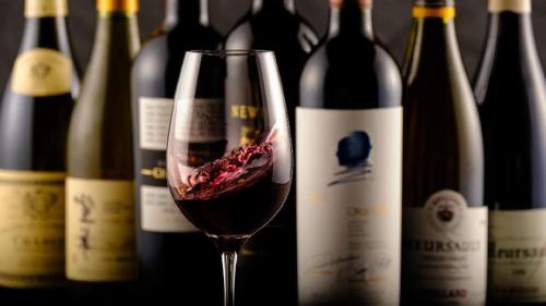 a glass of wine next to a bunch of wine bottles at Yufuin Luxury Villa -zakuro- in Yufuin