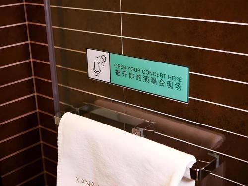 a sign in a bathroom with a towel at Xana Hotelle·Ji'nan Hi-tech Zone Century Avenue Tangye in Jinan