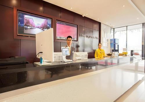 two men sitting at a counter in a lobby at City Comfort Inn Liuzhou The Mixc Xijiang Road in Liuzhou