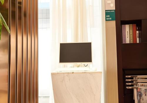 a computer monitor sitting on a desk next to a window at City Comfort Inn Liuzhou The Mixc Xijiang Road in Liuzhou