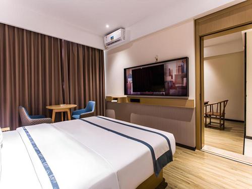 a hotel room with a bed and a flat screen tv at City Comfort Inn Liuzhou Wuling Liutai Road in Liuzhou