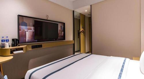 a hotel room with a bed and a flat screen tv at City Comfort Inn Liuzhou Wuling Liutai Road in Liuzhou