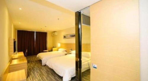 a hotel room with two beds and a mirror at City Comfort Inn Yichang Dongshan Three Gorges University Shuiyuecheng in Yichang