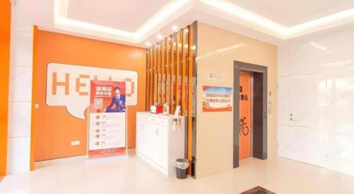 a room with an orange wall with a refrigerator in it at Shell Hotel Yangzhou Yangzijiang Bei Road Slender West Lake Scenic Area in Yangzhou