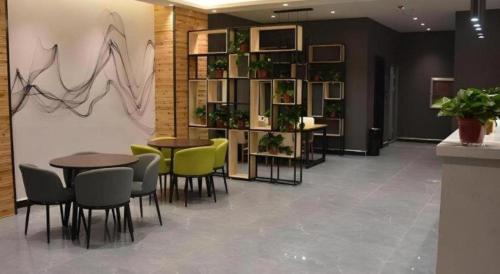 a restaurant with tables and chairs and a shelf with plants at Shell Hotel Kaifeng Jin'an Road Bianxihu Wanda Plaza in Kaifeng
