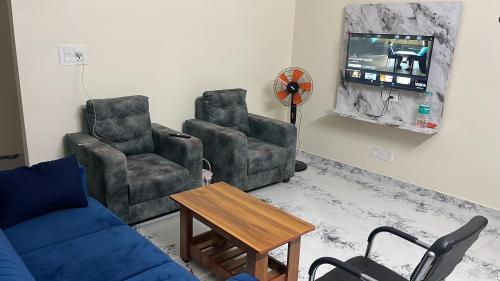 a living room with a couch and two chairs and a tv at THE ROYAL RETREAT service apartment in Chikmagalūr