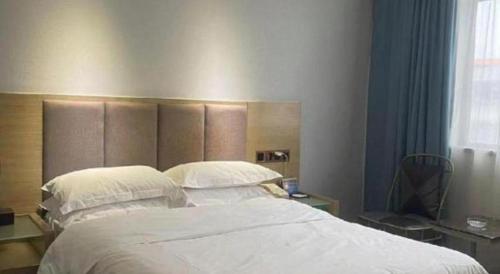 a bedroom with a large bed with white sheets and pillows at Borrman Hotel Huizhou West Lake Shuidong Street in Huizhou
