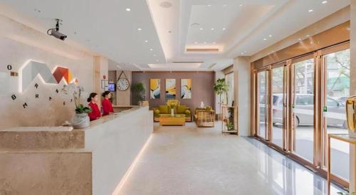 a lobby with two people sitting at a waiting room at Borrman Hotel Huizhou West Lake Shuidong Street in Huizhou