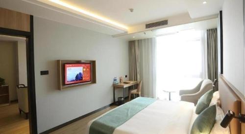 a bedroom with a bed and a tv on a wall at GreenTree Inn Anqing Yingbin Dong Road High-Speed Railway Station in Anqing