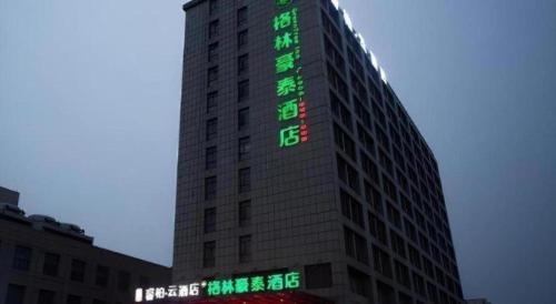 a tall building with green signs on the side of it at GreenTree Inn Anqing Yingbin Dong Road High-Speed Railway Station in Anqing