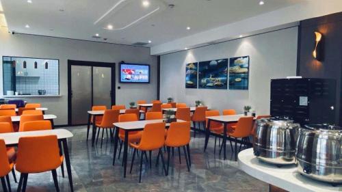 a dining room with tables and orange chairs at GreenTree Inn Express Datong High-Speed Railway Station Wanda Plaza Fangte in Datong