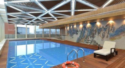 a pool in a building with a chair and a chair at Balan International Hotel in Dujiangyan