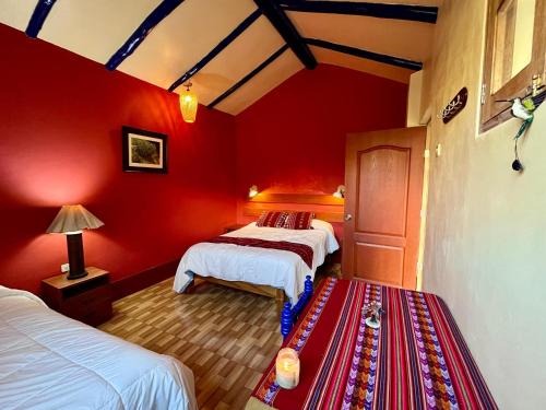 a red room with two beds and a red wall at La Casita de mi Abuela in Mancos