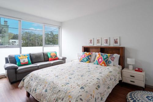 a bedroom with a bed and a couch and windows at Stylish 2BR Brunswick Home in Melbourne