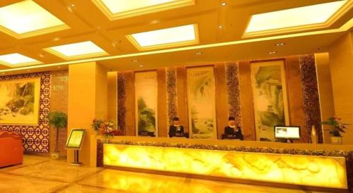 a hotel lobby with two people in front of a counter at VX Hotel Chengdu Jiaolong Port Haibin in Chengdu