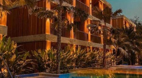 a hotel with palm trees in front of a building at Riverton Hotel in Samut Songkhram