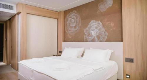 a bedroom with a white bed with a painting on the wall at Riverton Hotel in Samut Songkhram