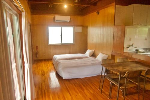a bedroom with a bed and a table in it at guest house HIBISCUS - Vacation STAY 87092 in Janagusuiku