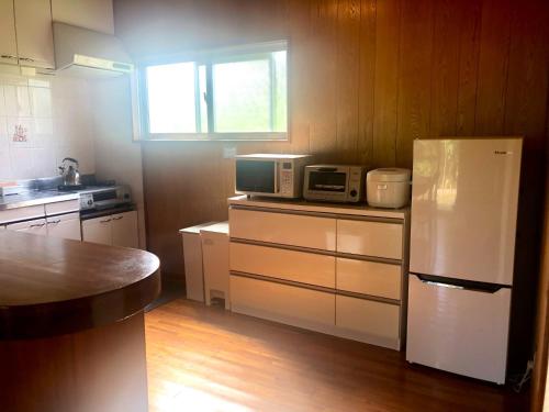 a kitchen with a white refrigerator and a microwave at guest house HIBISCUS - Vacation STAY 87092 in Janagusuiku