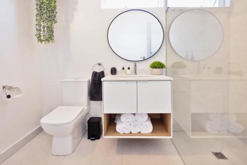 a white bathroom with a toilet and a sink at The Ya Ya Apartment in Stellenbosch