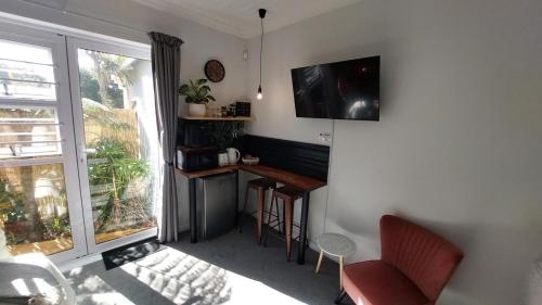 a living room with a table and a television on a wall at The Little Homestead in Gqeberha