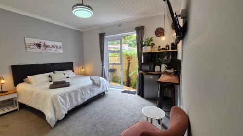 a bedroom with a bed and a large window at The Little Homestead in Gqeberha