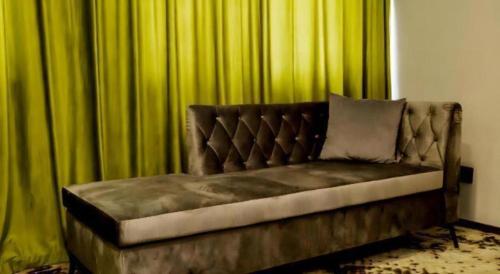 a couch sitting in front of green curtains at Borrman Hotel Jining High-tech Huangtun in Jining